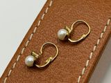 brown leather belt with pearl earrings on white surface