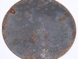 an old metal plate with rusted paint on it sitting on a white surface