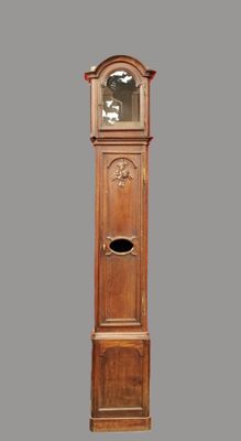 une grande horloge comtoise en bois sur un fond gris