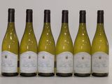 six bottles of white wine lined up in a row on a table
