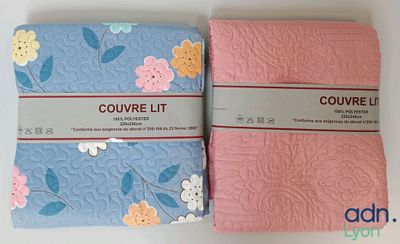 two pink and blue quilts with flowers on them sitting on a table
