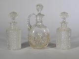 trois bouteilles en verre et une carafe posées sur une table