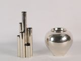 a silver vase next to a silver vase on a white surface