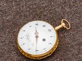 une montre de poche en or posée sur une surface marron