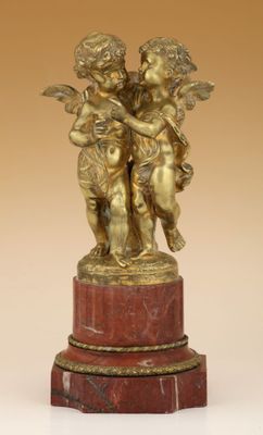 une figurine antique en bronze représentant deux chérubins, posée sur un socle en marbre