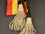 two pieces of cloth with tassels on a black surface