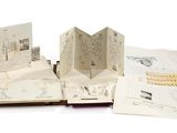 plusieurs livres ouverts, sur lesquels figurent des dessins, posés sur une surface blanche
