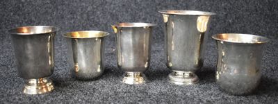 four silver cups are lined up on a black surface