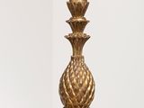 gold pineapple table lamp on a white pedestal with a white background