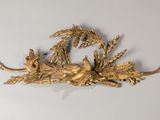 une sculpture en or représentant un oiseau perché sur une branche feuillue