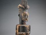 une vieille statue en bois d'un homme avec un chapeau sur la tête