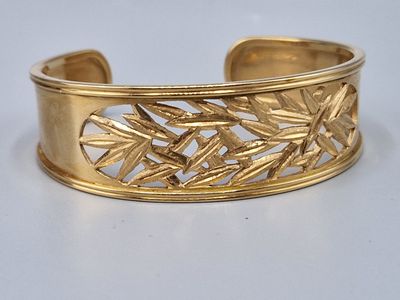 une image représentant un bracelet manchette en or orné de feuilles