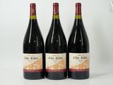 three bottles of red wine are lined up on a white surface