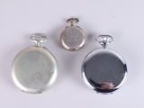 two silver pocket watches and a silver pocket watch on a white surface