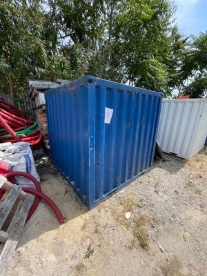 un bac bleu posé par terre à côté d'un tas de tuyaux