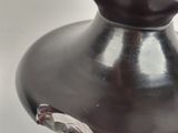 a black vase with a red flower on top of it