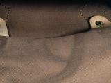 a brown purse with two green eyes inside of it