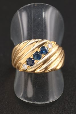 gros plan d'une bague en or avec saphirs bleus et diamants