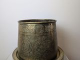 a large brass pot sitting on top of a marble table