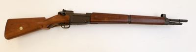un vieux fusil posé sur une surface blanche, muni d'une crosse en bois