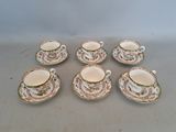 six tasses et soucoupes ornées de motifs floraux, posées sur une table