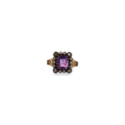 a close up of a ring with a purple stone surrounded by pearls