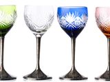 four different colored wine glasses sitting next to each other on a white surface