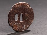 une petite pièce de bronze posée sur une table, dont l'ombre se projette sur le sol