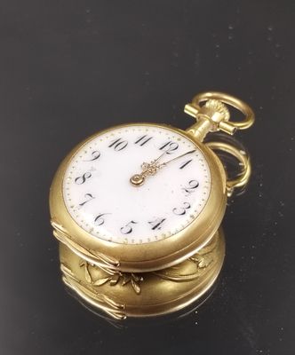 une montre de poche en or posée sur une surface noire avec un fond noir