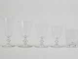 six clear wine glasses lined up in a row on a white surface