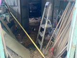 a room with a ladder, ladders, and a pile of wood