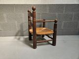 a small wooden chair with a wicker seat on a cement floor