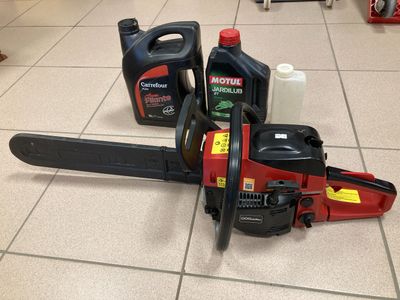 a picture of a chainsaw on the floor next to a can of motor oil