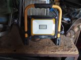 a yellow and black work light sitting on top of a wooden table