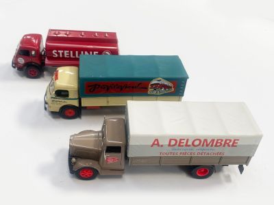 trois camions miniatures posés les uns à côté des autres sur une surface blanche