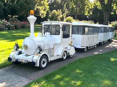 un petit train blanc garé sur le bord de la route