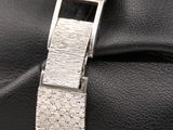 a close up of a silver bracelet on a black leather glove