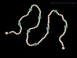 un gros plan sur un collier composé de perles et d'une perle verte