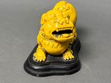 yellow statue of a dog on a black base on a gray surface