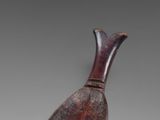 a brown vase with a wooden handle sitting on top of a table