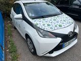 une petite voiture blanche avec un motif vert et bleu sur le capot