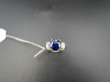 a close up of a blue sapphire and diamond ring on a black surface