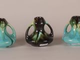 three different colored vases are lined up on a white surface