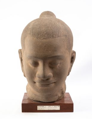 statue représentant la tête d'un homme, posée sur un socle en bois, sur fond blanc