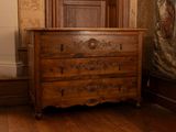 une commode dans une pièce où est accroché un tableau au mur