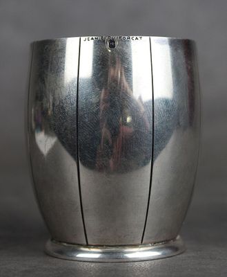 une coupe en argent posée sur une table, avec le reflet d'une personne en arrière-plan
