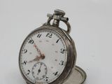 a silver pocket watch sitting on top of a white surface
