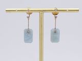 a pair of earrings with blue stone hanging from them on a gold stand