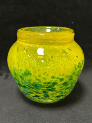 un vase jaune et vert posé sur une surface noire