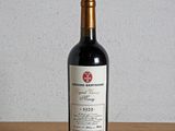 a bottle of red wine sitting on a wooden table